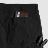Close-up of black Field Shorts showing the back pocket holding a brown wallet and an additional tool in the side pocket, highlighting the shorts' practical storage features.