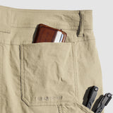 Close-up of tan Field Shorts back pocket with a brown wallet partially inside and multitool handles visible from a side pocket, highlighting durable fabric and stitching details.