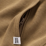 Close-up of a brown Smuggler French Terry Crew fabric showing a hidden zipper pocket and a woven tag with the text "STAY ZERO" on the seam.