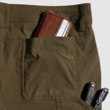 Close-up of olive green Field Shorts back pocket with a brown leather wallet and two black multitools partially visible inside.
