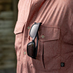 Close-up of a person wearing a reddish textured F'n Soft Daily Shirt with black sunglasses hooked onto the front pocket.