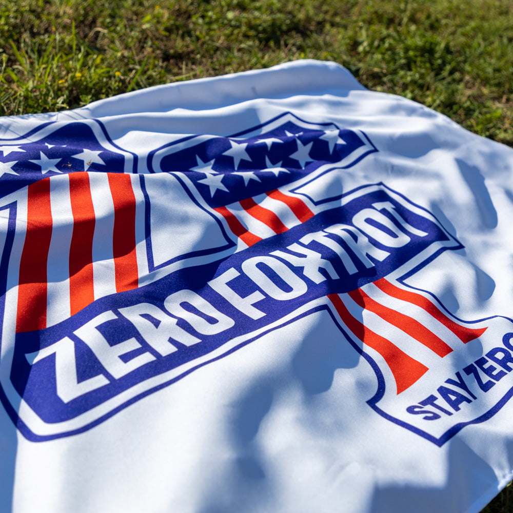 ZF Stars and Stripes Flag spread on grass with red white and blue stripes stars and bold Zero Foxtrot branding across the fabric