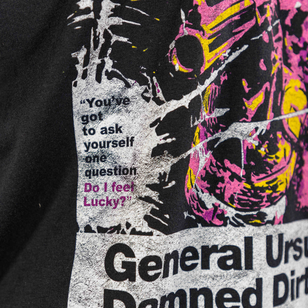 Close-up of a black Damned Dirty Ape Tee featuring a distressed graphic with the quote "You've got to ask yourself one question Do I feel Lucky?" in white and pink text.