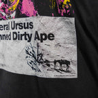 Close-up of a black Damned Dirty Ape Tee featuring a vintage-style print with text and a small graphic of horses near a rocky landscape.