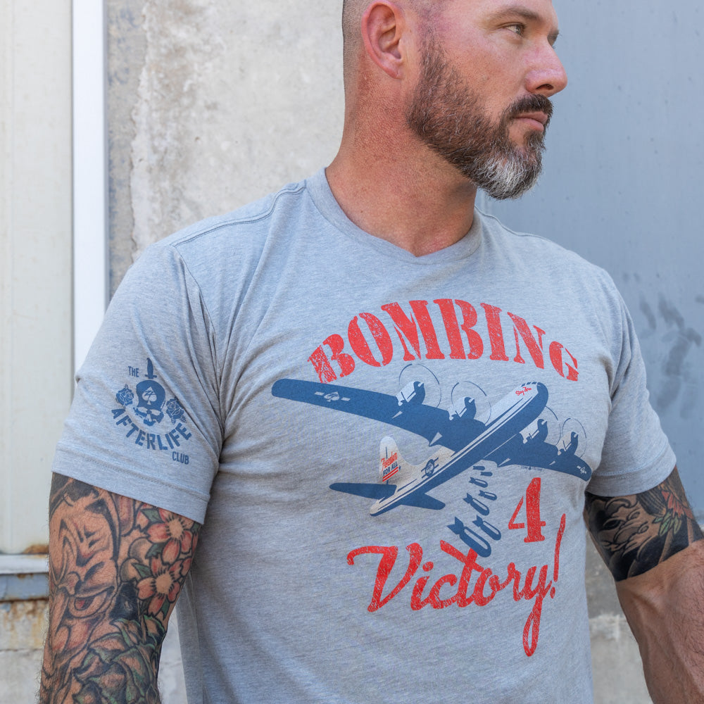 Bombing For Victory Tee in grey featuring a red and blue bomber plane graphic with Victory lettering and a skull emblem on the sleeve