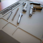 ZF Gun Cleaning Mat laid out with a disassembled handgun, including the slide, barrel, recoil spring, and frame, on a durable, non-slip surface designed for firearm maintenance.