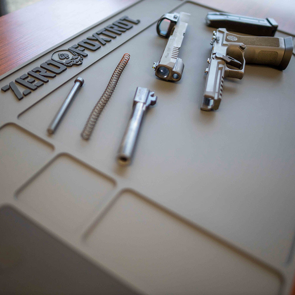 ZF Gun Cleaning Mat laid out with a disassembled handgun, including the slide, barrel, recoil spring, and frame, on a durable, non-slip surface designed for firearm maintenance.