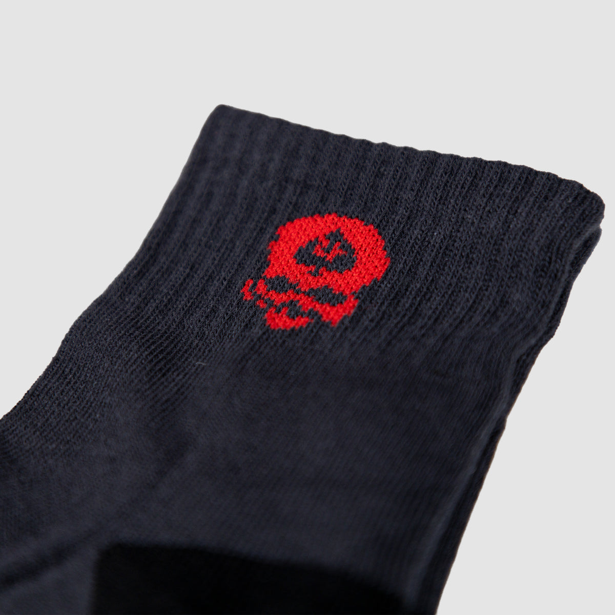 Close-up of a black sock cuff featuring a small red skull design, part of the Zero Ankle Socks - Black Tiger Stripe and Grey collection.
