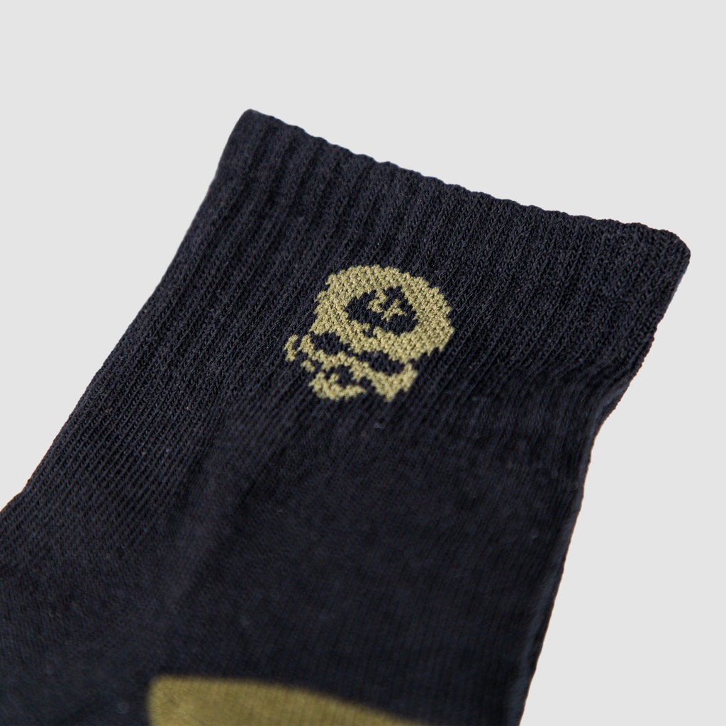 Close-up of the cuff area of a Zero Ankle Socks - Advisor Tiger Jungle and Black, showing black fabric with a small yellow skull design knitted near the top edge.