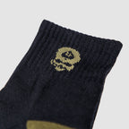 Close-up of the cuff area of a Zero Ankle Socks - Advisor Tiger Jungle and Black, showing black fabric with a small yellow skull design knitted near the top edge.