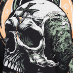 Close-up of a detailed graphic print featuring a skull with a cross on its forehead in muted green and orange tones on a black fabric, part of the Without Fear Tee design.
