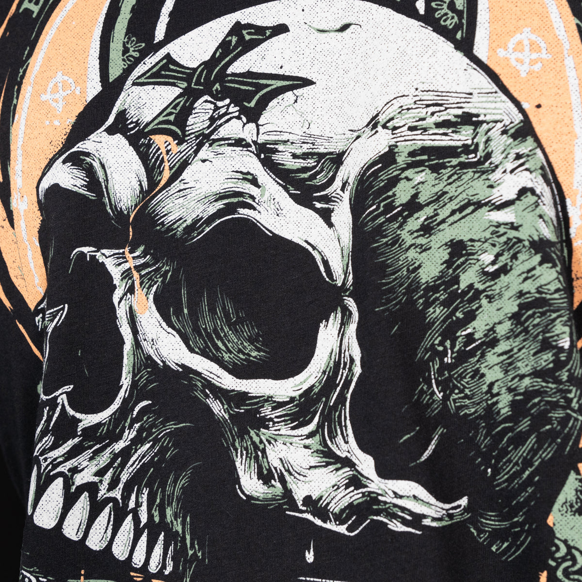 Close-up of a detailed graphic print featuring a skull with a cross on its forehead in muted green and orange tones on a black fabric, part of the Without Fear Tee design.