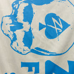 Close-up of blue graphic design on a light beige microfiber fabric showing details of a skull with a heart and arrow motif on the Microfiber Beach Towel (2025).