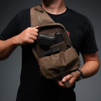 Surplus EDC Sling worn across the chest in brown with a zippered open compartment showing a secured handgun and spare magazine contents