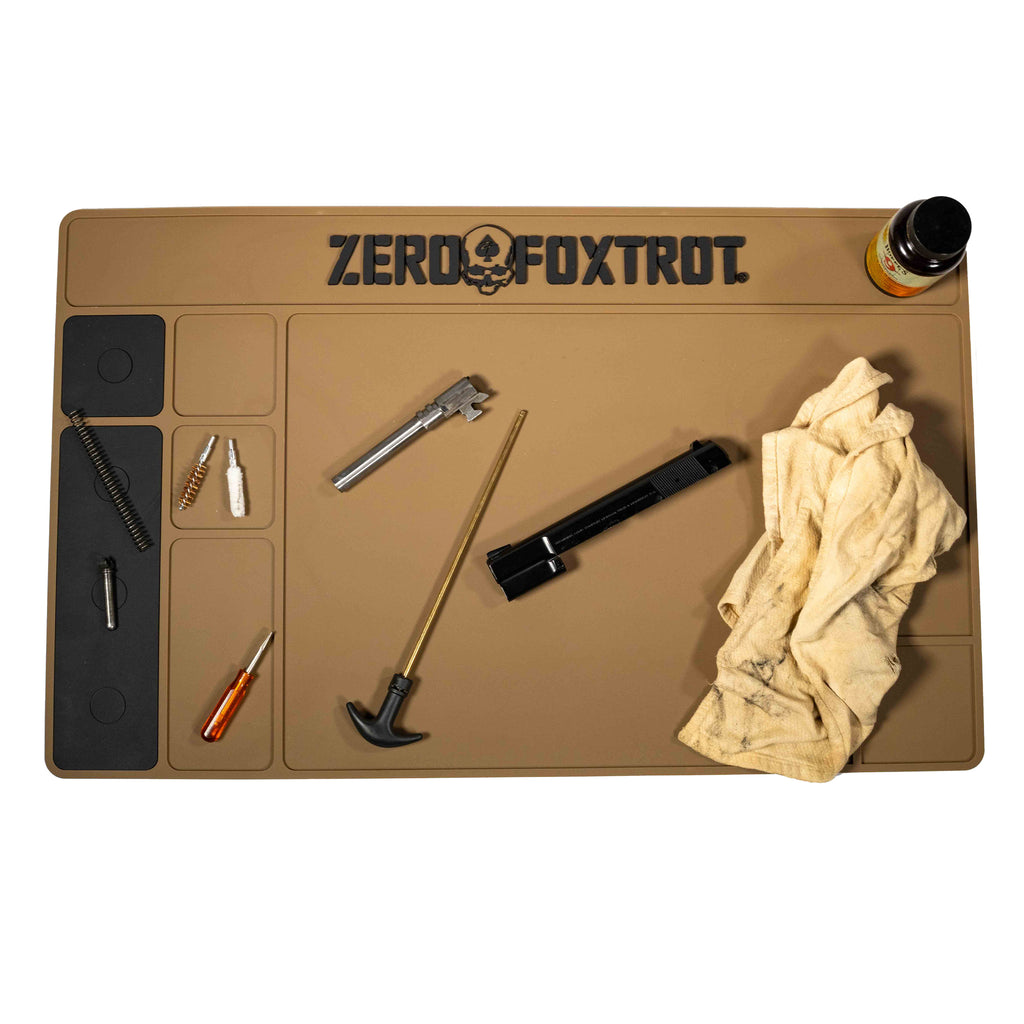 ZF Gun Cleaning Mat in tan color with multiple compartments holding gun cleaning tools including brushes, screwdriver, gun parts, a cloth, and a small bottle.