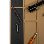 Close-up view of gun parts and tools arranged on a tan and black ZF Gun Cleaning Mat designed for organized firearm maintenance.