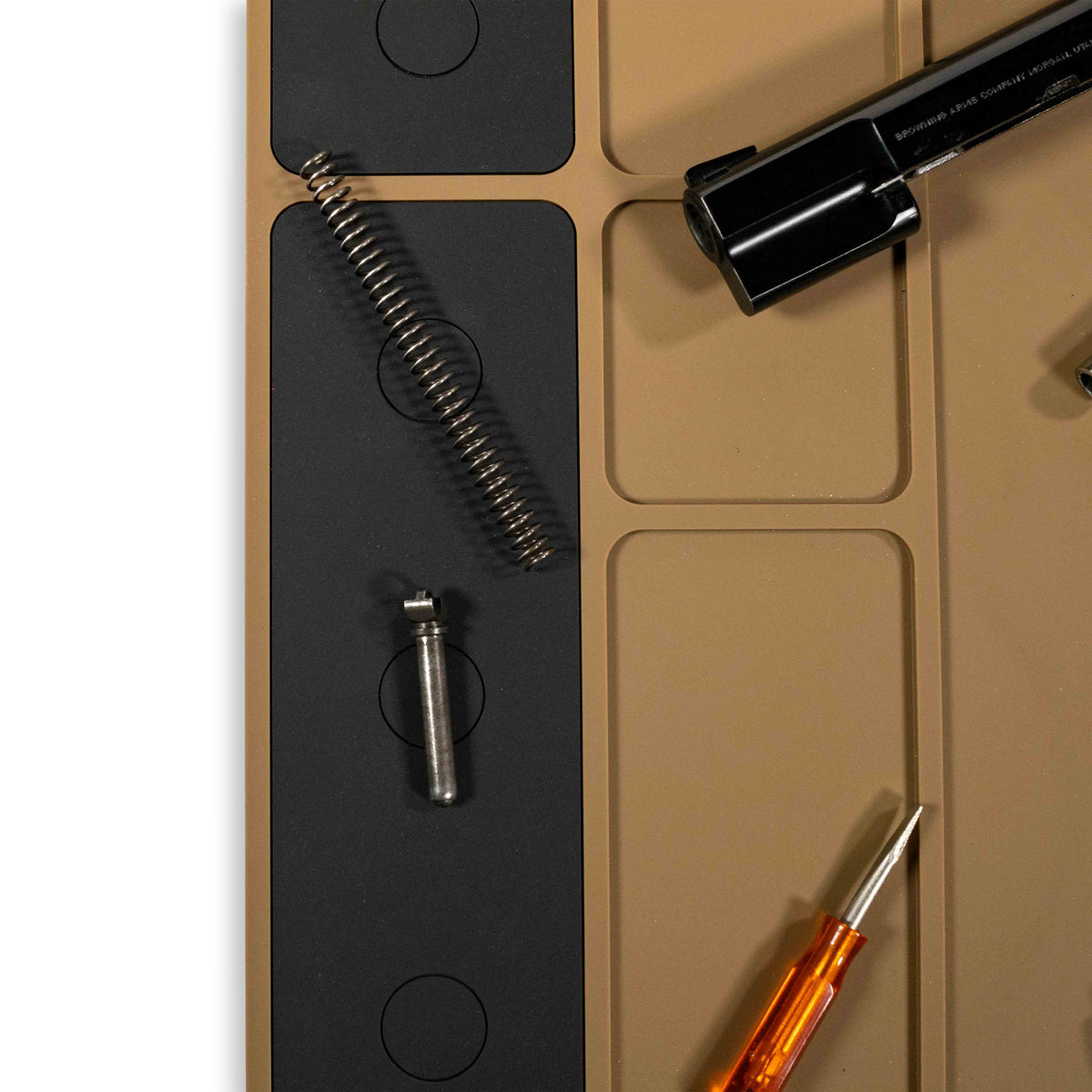 Close-up view of gun parts and tools arranged on a tan and black ZF Gun Cleaning Mat designed for organized firearm maintenance.