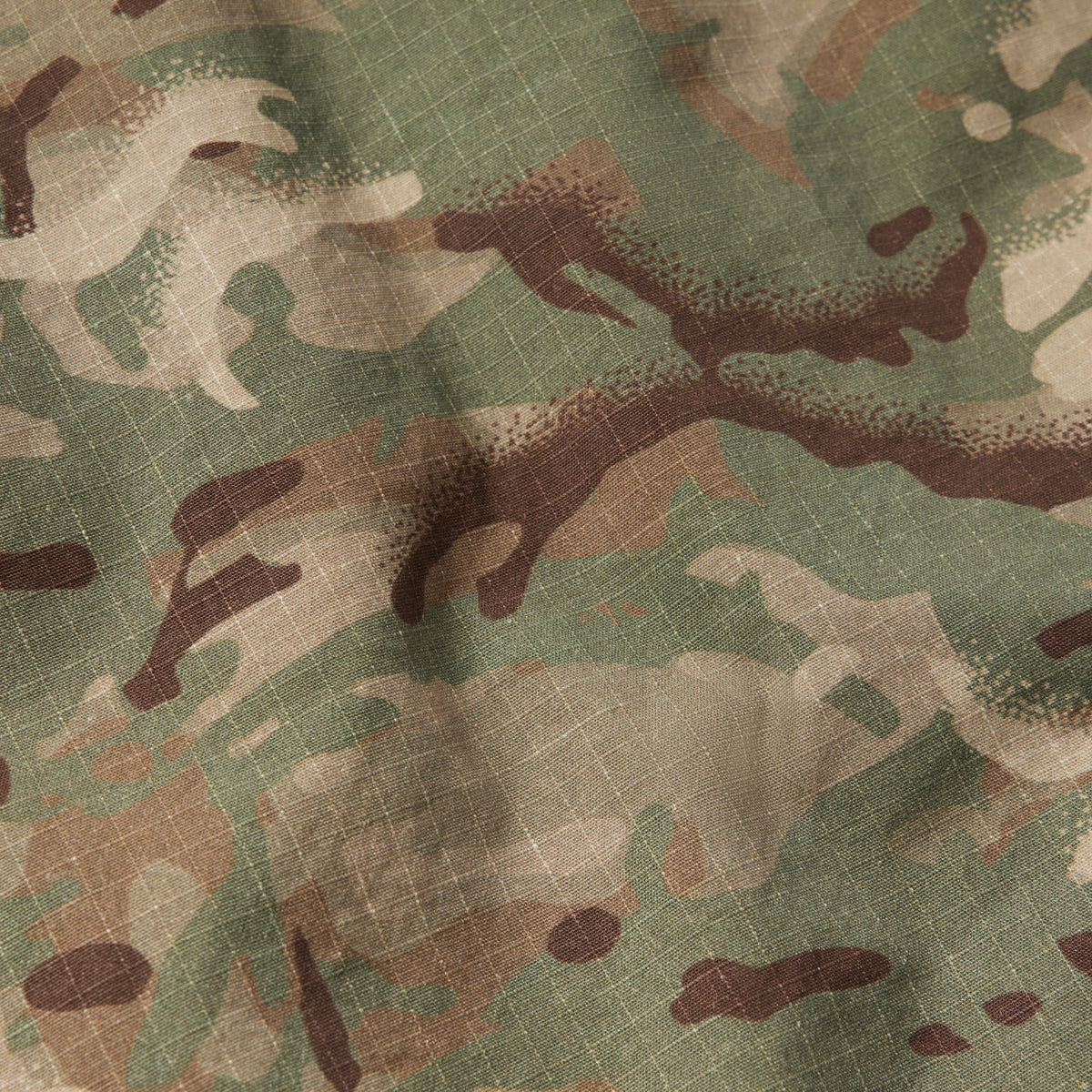 Close-up of fabric with green, brown, and beige camouflage pattern and textured weave, part of the CPO Shirt material.