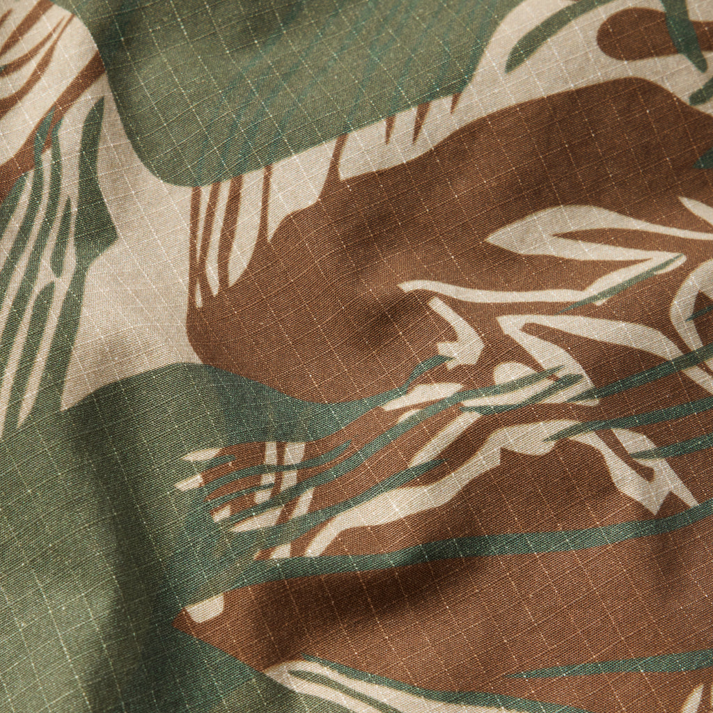 Close-up of fabric in green, brown, and tan brushstroke camouflage pattern with a grid texture detail, part of the CPO Shirt material.