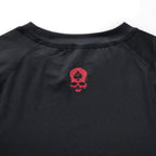 Compression Long Sleeve Rash Guard in black with a crew neckline, stitched seams, and a red skull graphic on the chest”】【