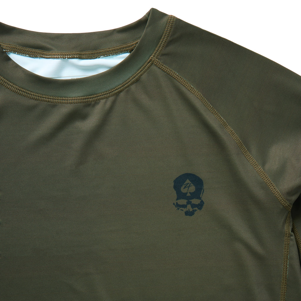 Compression Long Sleeve Rash Guard in olive green with crew neckline, flatlock stitching, and a small skull graphic on the chest