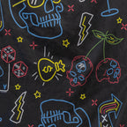 Close-up of a black microfiber fabric with colorful neon-style illustrations including skulls, cherries, dice, lightning bolts, stars, and a money bag, part of the Microfiber Beach Towel (2025).