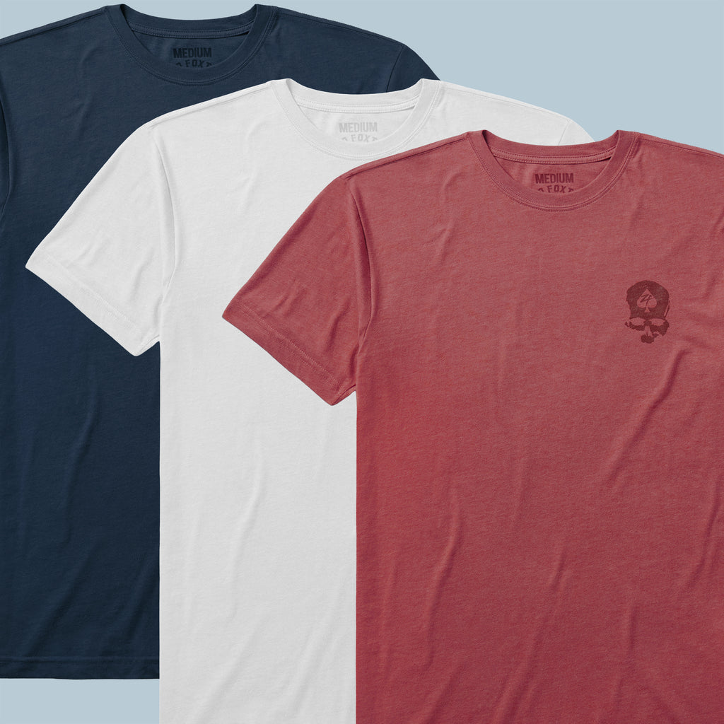 Three neatly laid out ZF Core Tee 250th Birthday 3-Pack shirts in navy blue, white, and red with a subtle printed design on the chest of the red shirt.