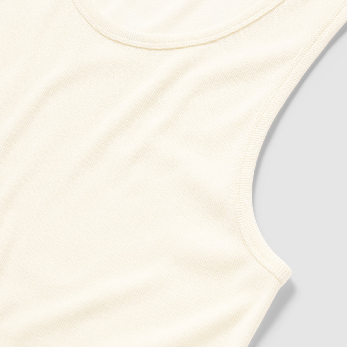 Close-up of a soft, white ribbed cotton Skivvy Tank showing its sleeveless design and rounded neckline on a light background.