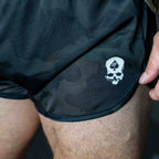 Close-up of a person wearing ZF Silkies - Camos shorts featuring a subtle dark camouflage pattern and a small white skull logo on the front left side.