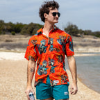 Surf Shirts (Last Chance) red short sleeve button up shirt with colorful ocean inspired pattern modeled by a man on a beach beside the water
