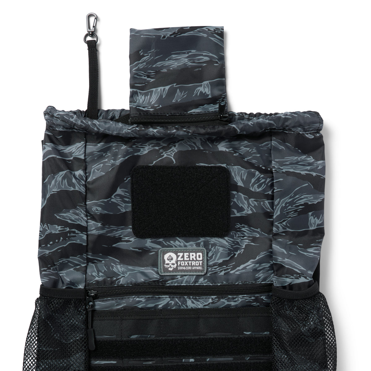 TAC Drawstring Pack in black and gray tiger stripe pattern with multiple compartments, mesh side pockets, and a top flap with a clip attachment.
