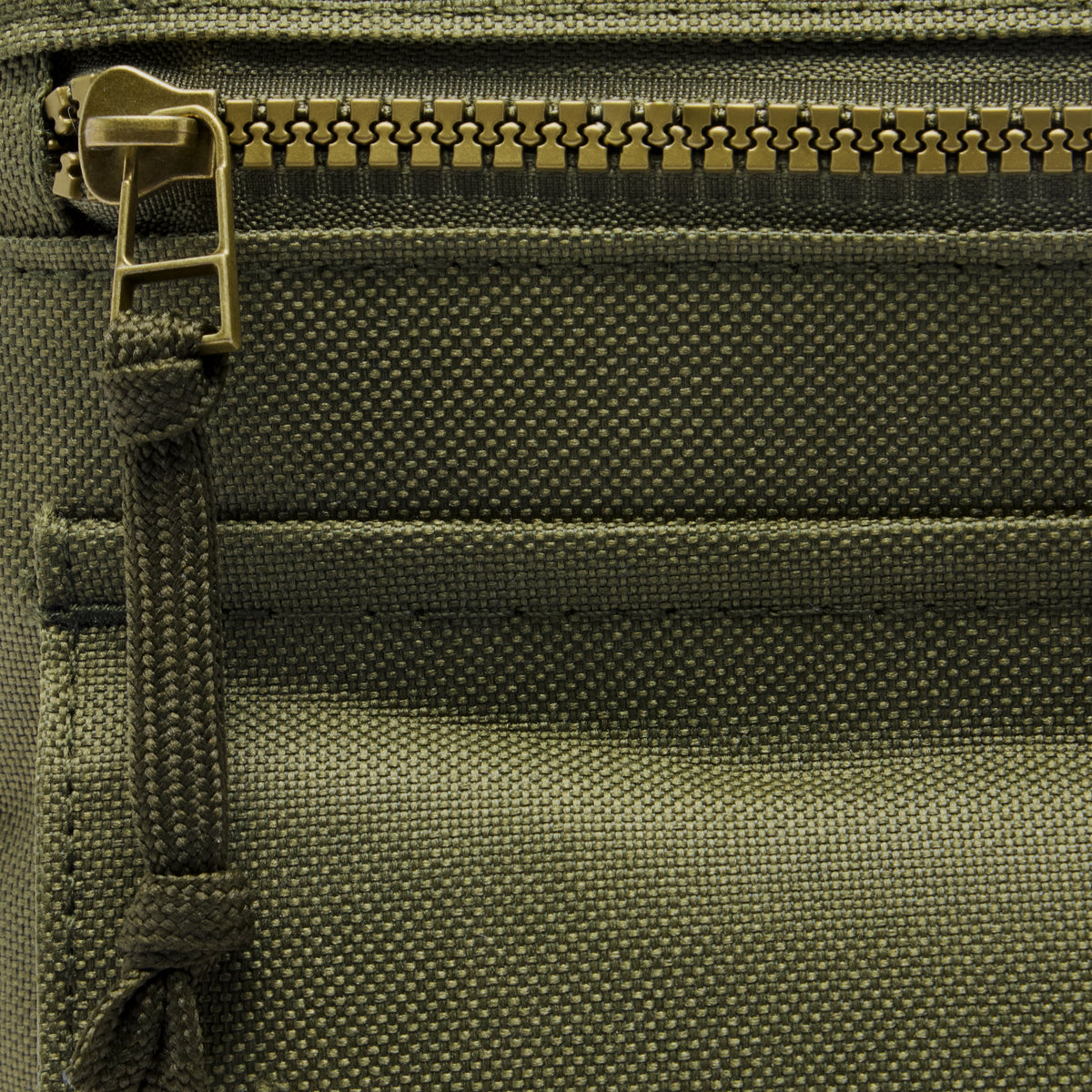 Surplus EDC Sling in olive green with a textured fabric interior, zippered compartment, and adjustable strap detail