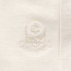 Close-up of an embroidered crest detail in matching bone white thread on the fabric of the Smuggler French Terry Zip Hoodie, highlighting its subtle texture and premium stitching.