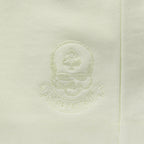 Close-up of a light sage green Smuggler French Terry Hoodie featuring a subtle embroidered skull and ace of spades logo on soft French terry fabric.