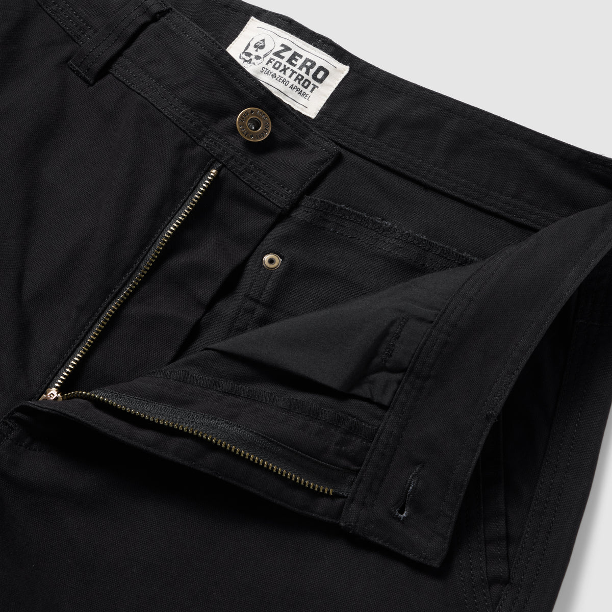 Foxhole 5 Pocket Pant in black, close-up of the waistband and open zip fly with button closure, belt loops, stitching, and interior construction