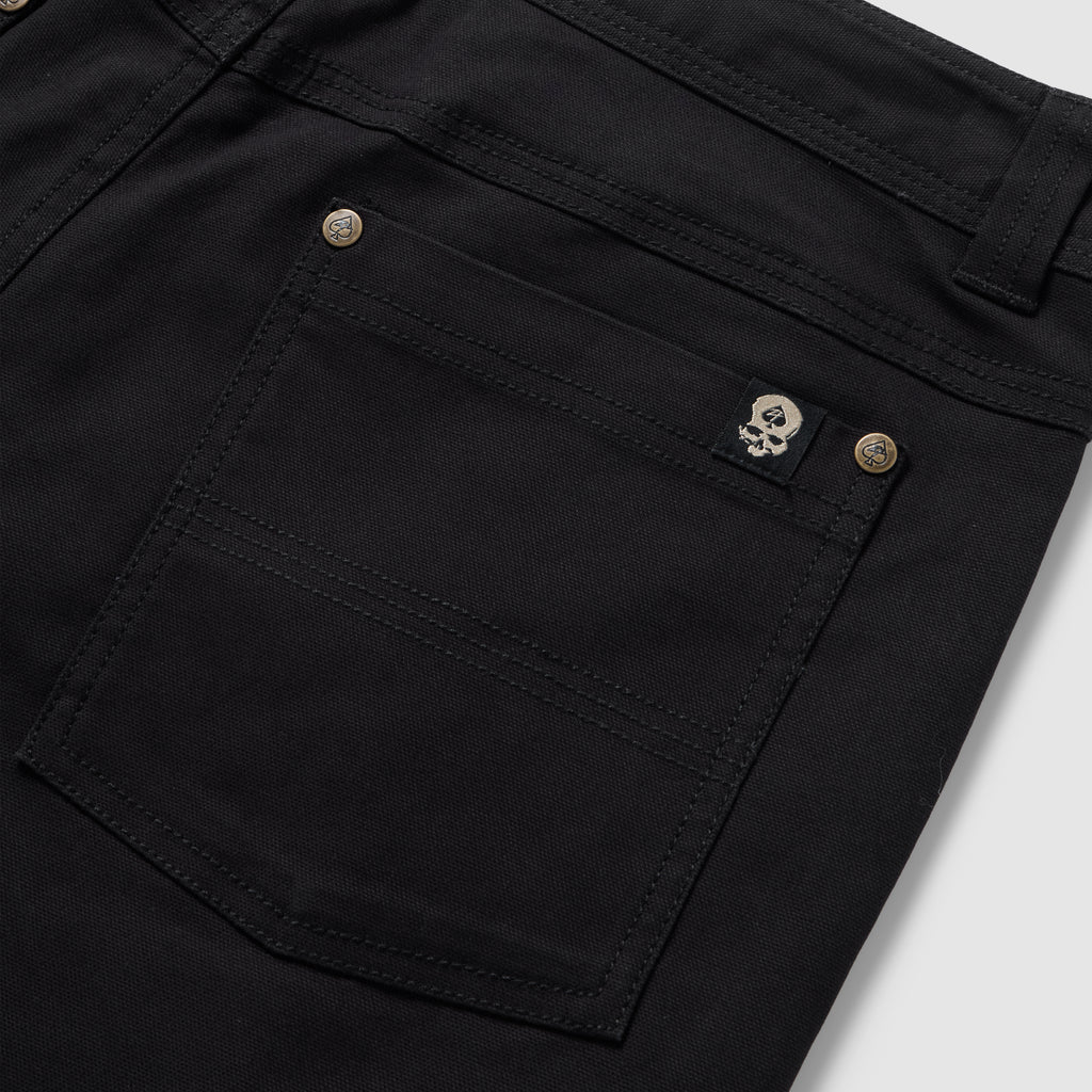 Foxhole 5 Pocket Pant in black with close-up details of the rear patch pocket, double stitching, button hardware, and skull logo tab