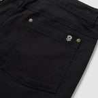 Foxhole 5 Pocket Pant in black with close-up details of the rear patch pocket, double stitching, button hardware, and skull logo tab