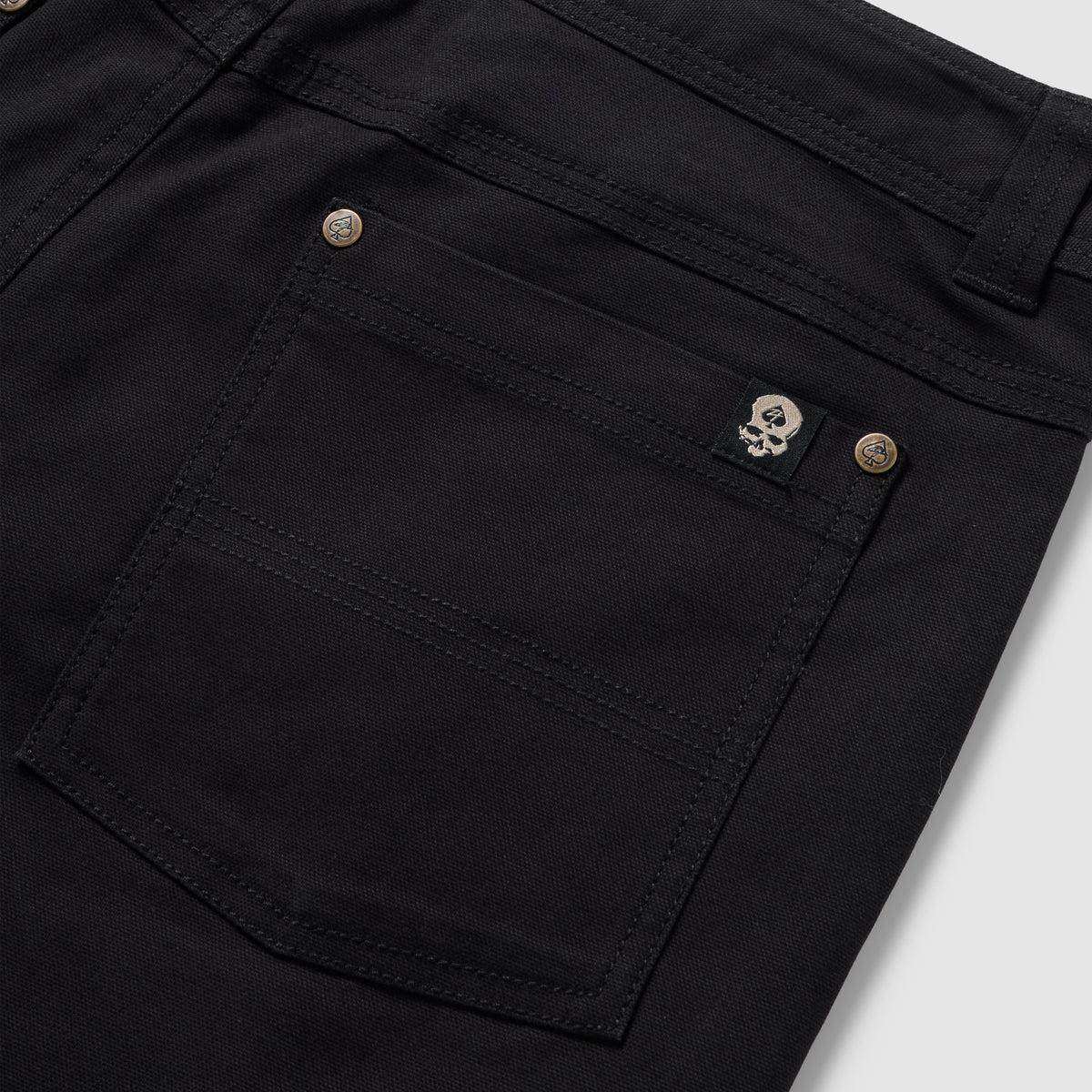 Foxhole 5 Pocket Pant in black with close-up details of the rear patch pocket, double stitching, button hardware, and skull logo tab