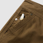 Foxhole 5 Pocket Pant in brown with a close up of the front pocket reinforced stitching metal rivets and a white tool tucked inside