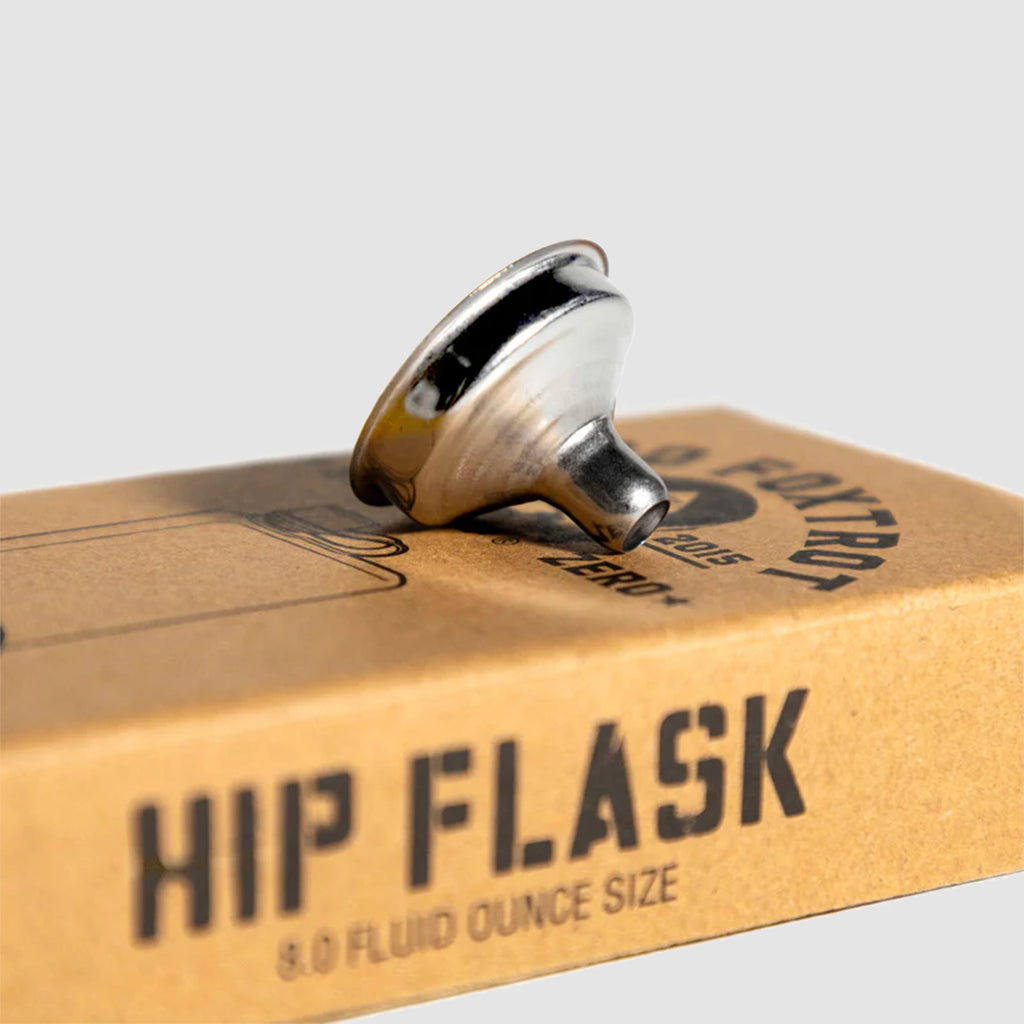 Chief Flask in polished silver metal, shown resting on its cardboard package labeled Hip Flask with a 9.0 fluid ounce size marking