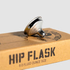 Chief Flask in polished silver metal, shown resting on its cardboard package labeled Hip Flask with a 9.0 fluid ounce size marking