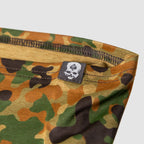 Close-up of a camo-patterned Performance Sun Gaiter made from lightweight fabric featuring durable stitching and a small black label with a white skull and spade logo.