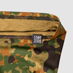 Close-up of a camouflage-patterned Performance Sun Gaiter with visible stitching and a small black tag reading STAY ZERO on the edge of the fabric.