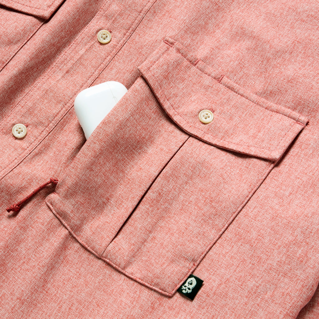 Close-up of the front pocket and buttons on a rust-colored F'n Soft Daily Shirt, showing fabric texture and a small black tag detail.