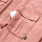 Close-up of the front pocket and buttons on a rust-colored F'n Soft Daily Shirt, showing fabric texture and a small black tag detail.