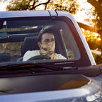 Man wearing a camouflage patterned Performance Sun Gaiter while driving a convertible vehicle with the top down during a sunny outdoor setting.