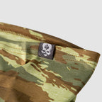 Close-up view of a camouflage patterned Performance Sun Gaiter showing detailed stitching and a small black tag with a skull and spade logo.