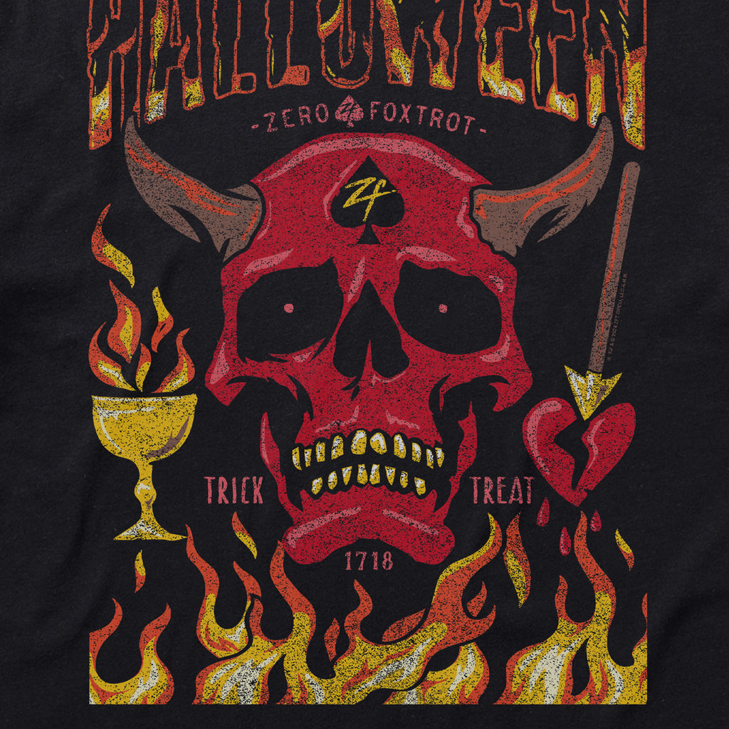 A graphic design on a Halloween No Quarter Tee featuring a red devil skull with horns, a spade symbol on the forehead, flames at the bottom, a burning chalice on the left, and a heart pierced by an arrow on the right with the words "Trick" and "Treat.