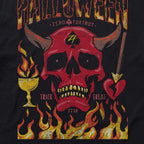 A graphic design on a Halloween No Quarter Tee featuring a red devil skull with horns, a spade symbol on the forehead, flames at the bottom, a burning chalice on the left, and a heart pierced by an arrow on the right with the words "Trick" and "Treat.