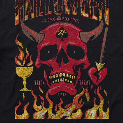 A graphic design on a Halloween No Quarter Tee featuring a red devil skull with horns, a spade symbol on the forehead, flames at the bottom, a burning chalice on the left, and a heart pierced by an arrow on the right with the words 